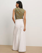 Veronica Beard Sleeveless green and brown patterned top with a twisted neckline and white wide-leg jeans.