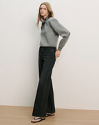 Veronica Beard Gray long-sleeve sweater with a high ruffled neck and black wide-leg jeans.