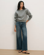 Veronica Beard Gray crewneck sweatshirt with raglan sleeves and dark wash wide-leg jeans with a raw hem.