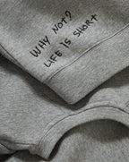 Veronica Beard Gray crewneck sweatshirt with raglan sleeves and dark wash wide-leg jeans with a raw hem.