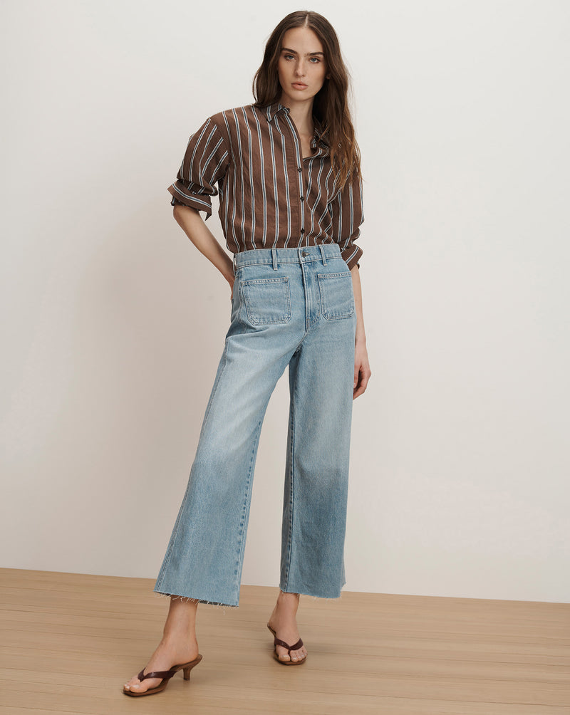 Veronica Beard Brown and white striped sheer button-up shirt with light wash wide-leg jeans.