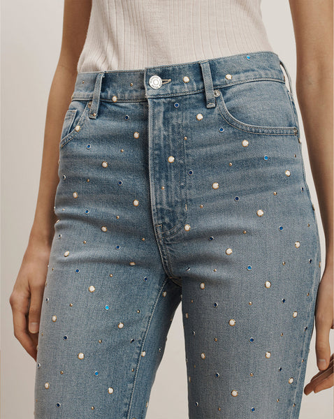 The image shows a pair of high-waisted, light-wash denim jeans with small white polka dots scattered across the fabric.
