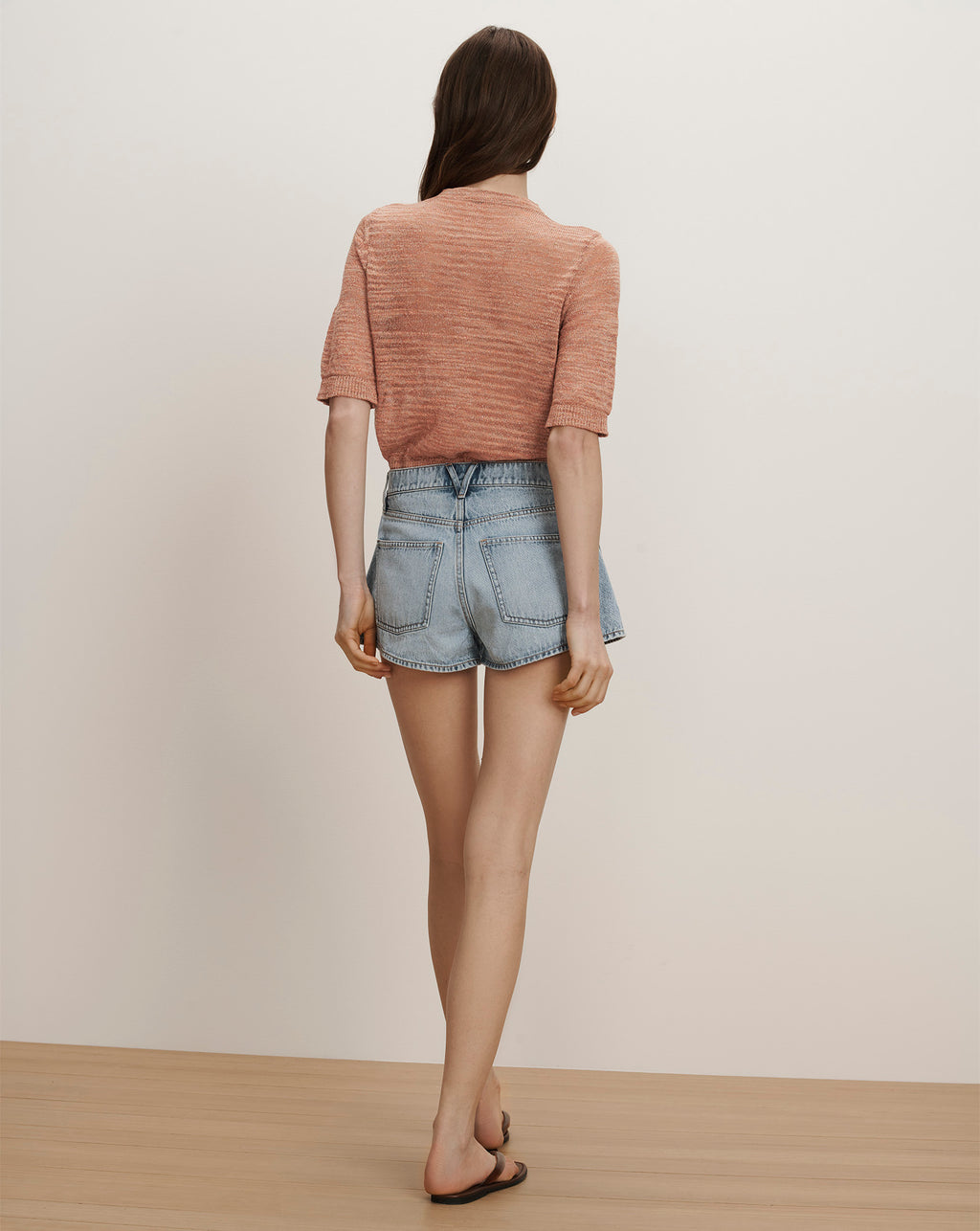Veronica Beard A peach short-sleeve knit top and light wash denim shorts with a scalloped hem.