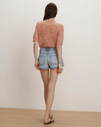 Veronica Beard A peach short-sleeve knit top and light wash denim shorts with a scalloped hem.