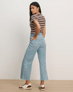 Veronica Beard Light wash wide-leg jeans with a raw hem and a brown and pink striped short-sleeve t-shirt.