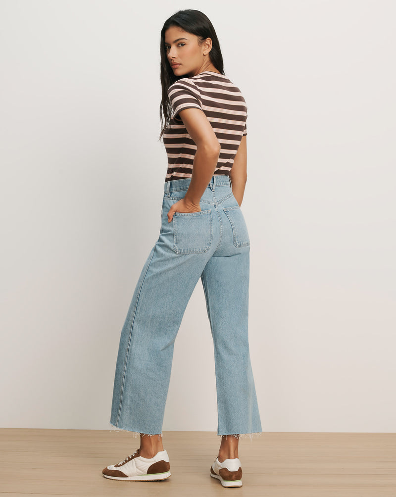 Veronica Beard Light wash wide-leg jeans with a raw hem and a brown and pink striped short-sleeve t-shirt.
