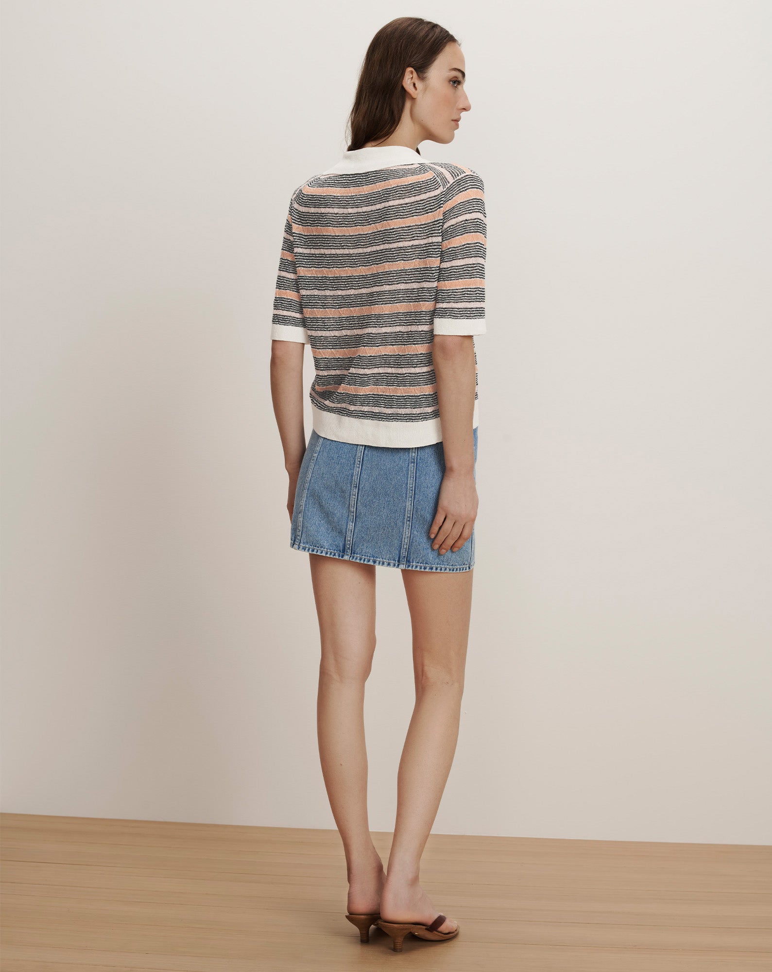Veronica Beard Gray, peach, and white striped knit polo shirt with short sleeves and a white collar, paired with a light wash denim mini skirt.