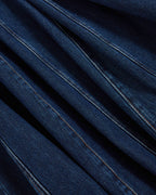 Veronica Beard Blue denim fabric with diagonal pleats and stitching.