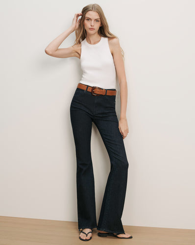 Veronica Beard White ribbed knit tank top, dark wash flared jeans, and a brown leather belt.