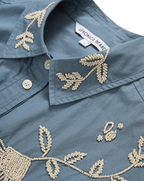 Veronica Beard Blue embroidered button-up shirt and cream wide-leg pants.
