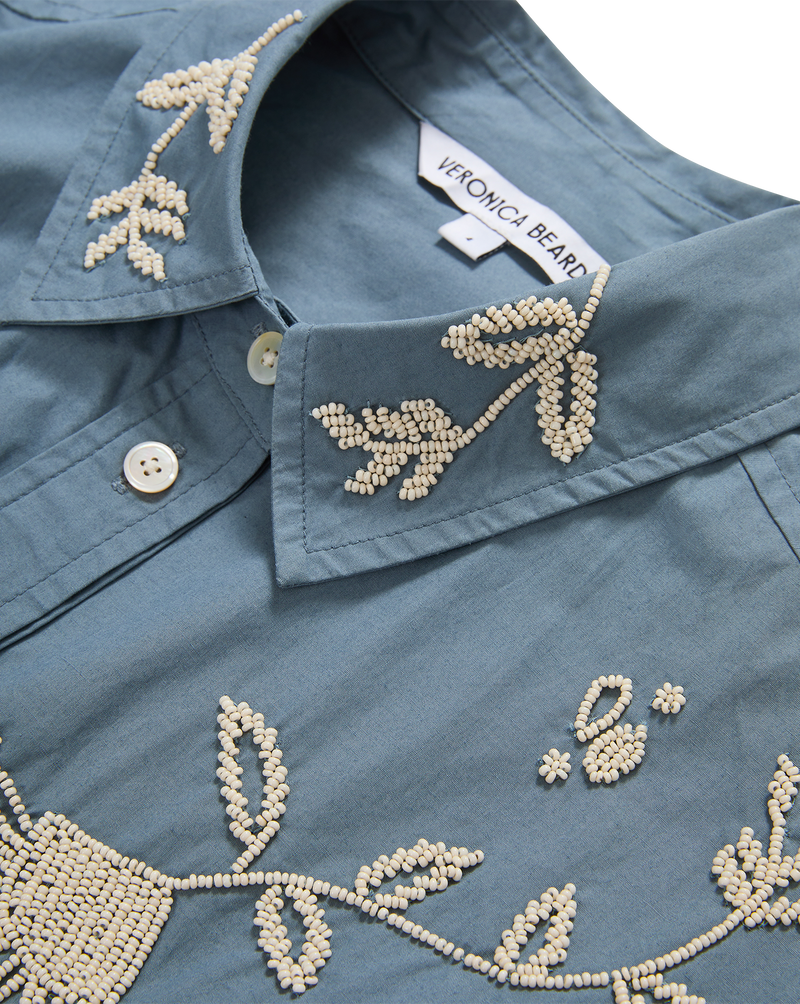 Veronica Beard Blue embroidered button-up shirt and cream wide-leg pants.