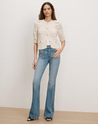 Veronica Beard Cream knit cardigan and blue flared jeans.