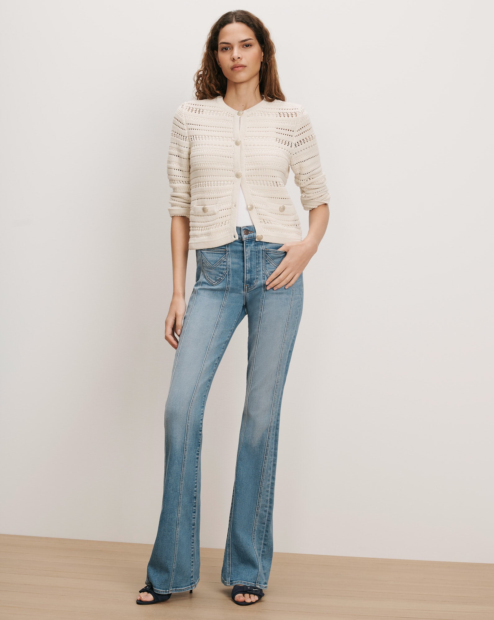 Veronica Beard Cream knit cardigan and blue flared jeans.
