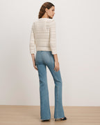Veronica Beard Cream open-knit cardigan and light wash flared jeans.