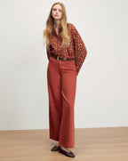 Veronica Beard Brown patterned button-up shirt and rust wide-leg jeans.